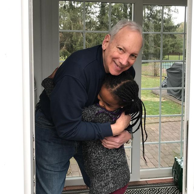 Stephen Kunken's father in a black shirt and pants with Naomi in a grey dress.